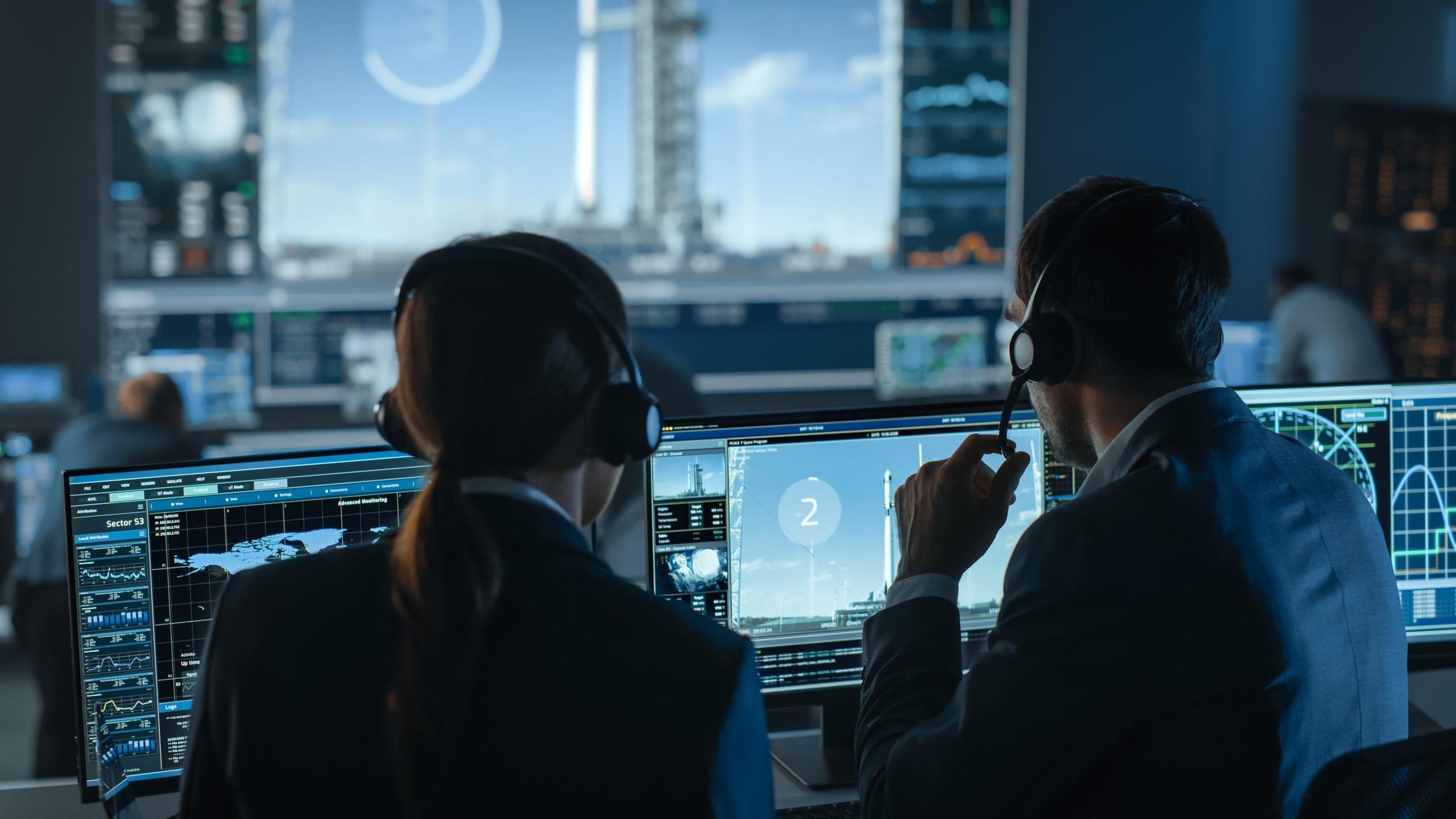 Flight Director Counts Down the Seconds Before Space Rocket Launch. Team in Mission Control Witness Successful Lift Off. Flight Control Employees Sit in Front of Computers and Monitor the Mission.
